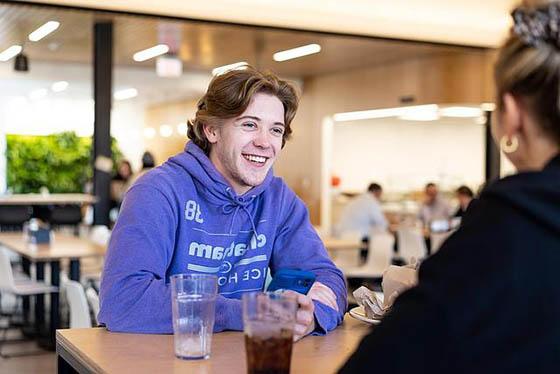 Smiling students sit together at a table in Anderson Dining Hall